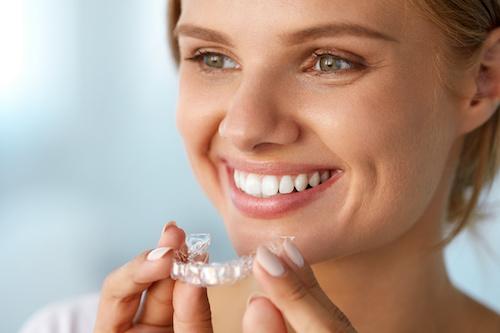 A woman putting in an Invisalign tray