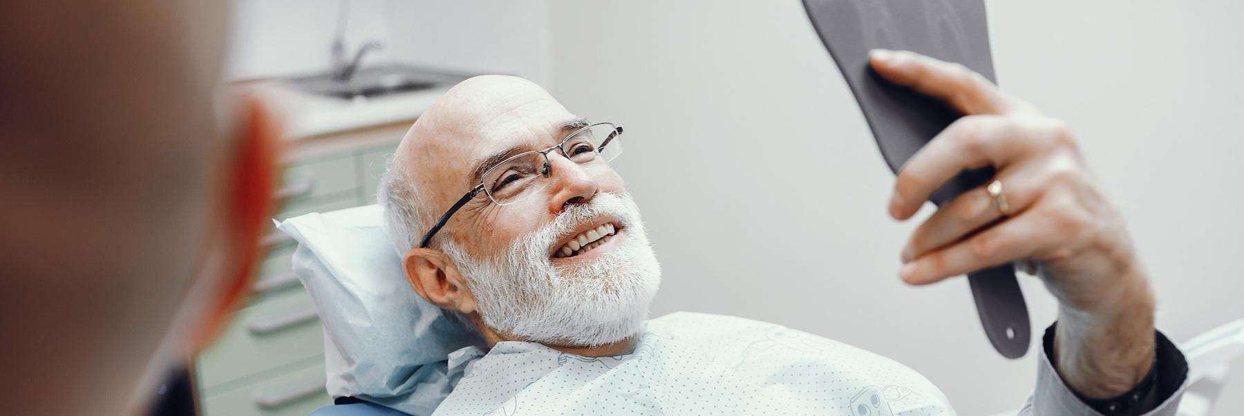 An older man looking at his dental implants during a dental appointment