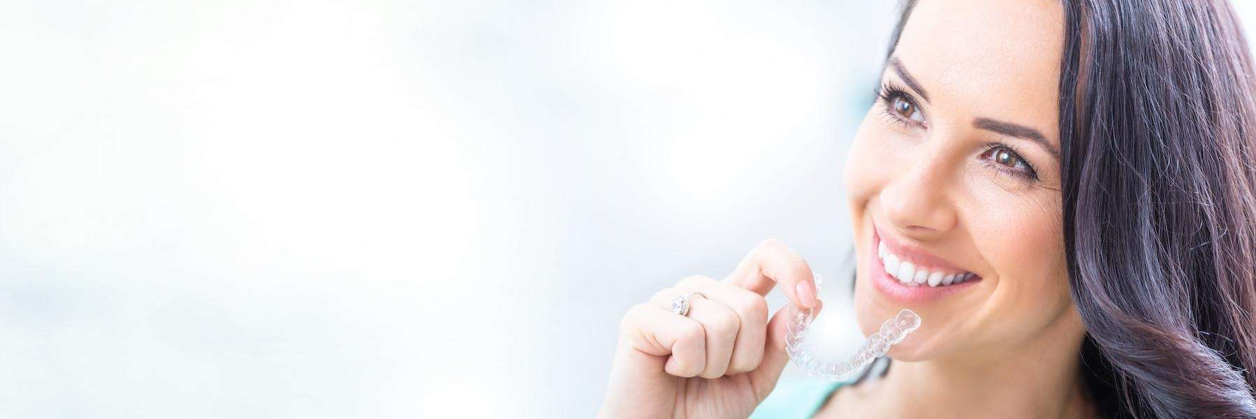 A woman holding her Invisalign Clear Aligner