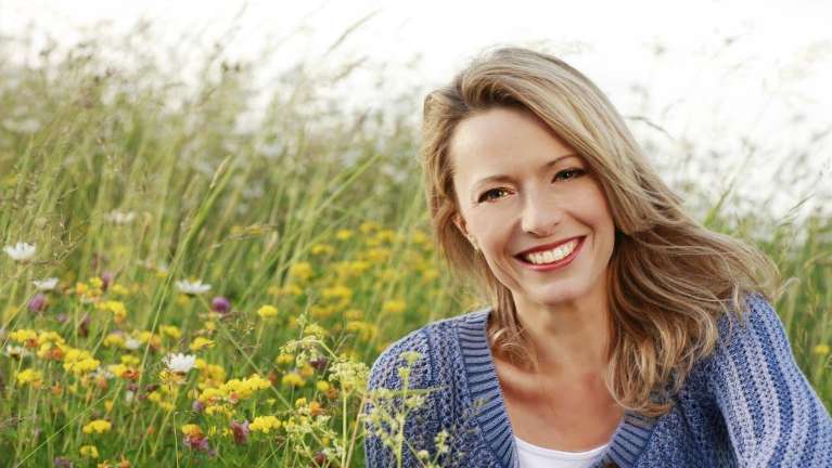 A woman smiling in a field | dental bridges in Elk Grove CA