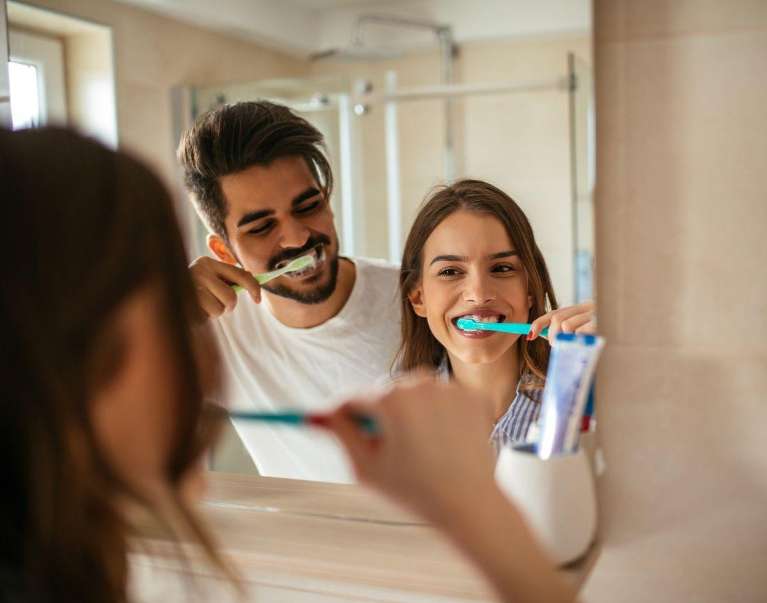 A couple brushing their teeth in the mirror