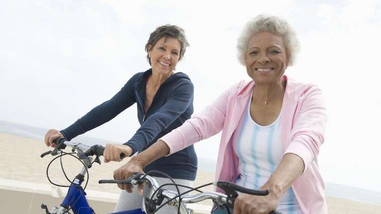 Two women riding bikes on the beach