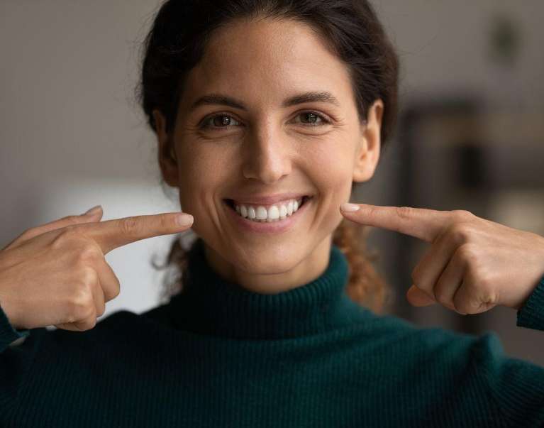 A woman pointing at her smile