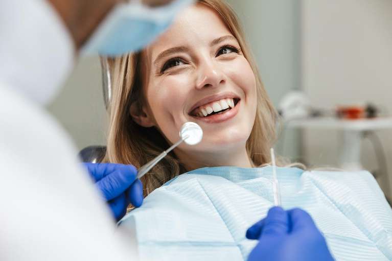 A smiling woman getting a dental exam | dentist Elk Grove, CA