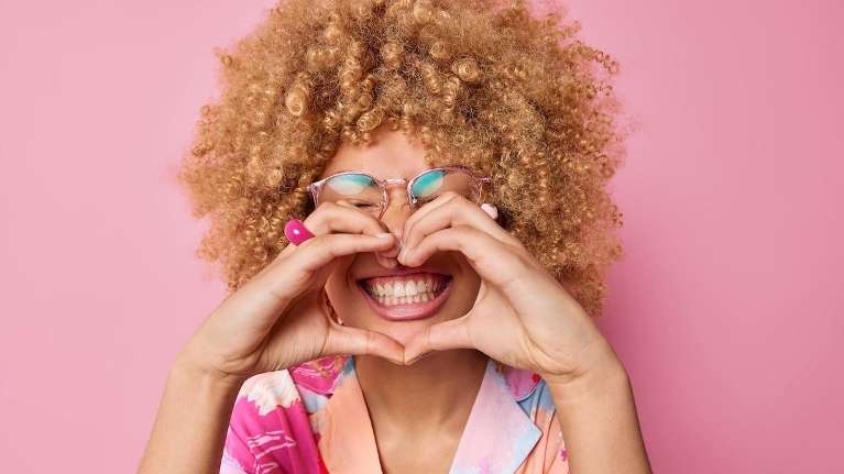 A smiling woman making a heart with her hands