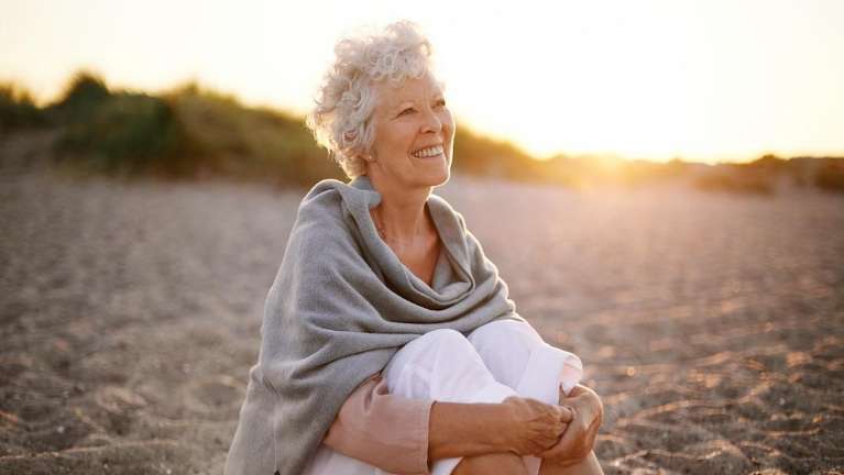 A smiling woman sitting in the sand