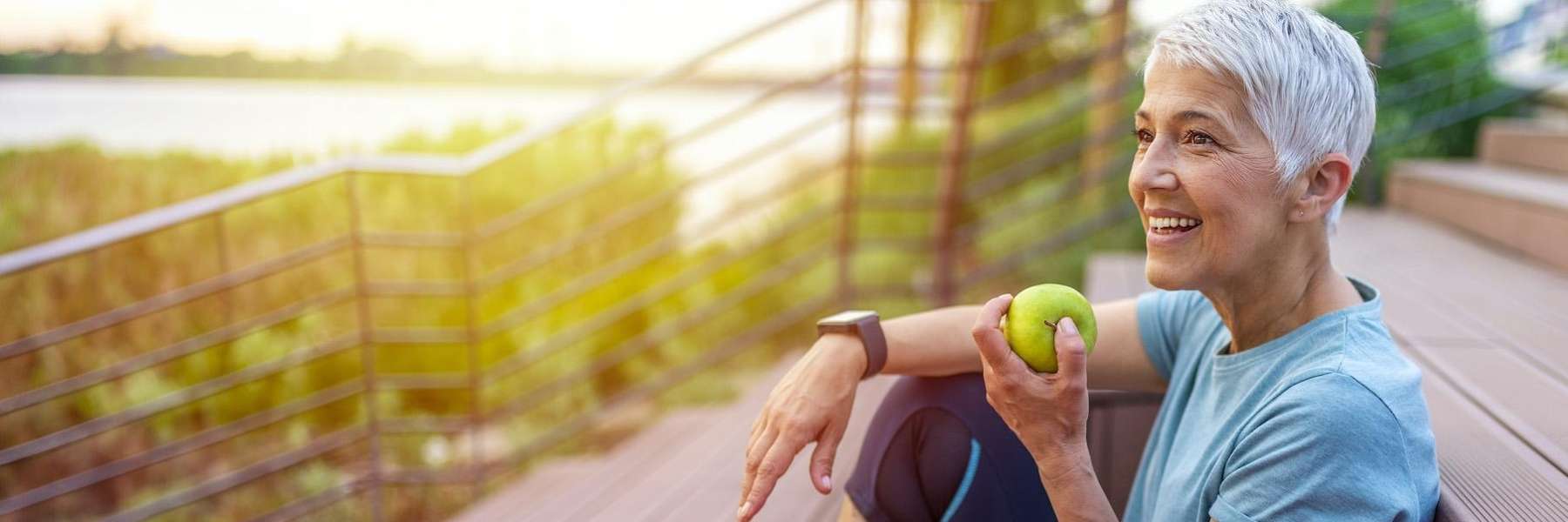 An older woman eating an apple on the stairs