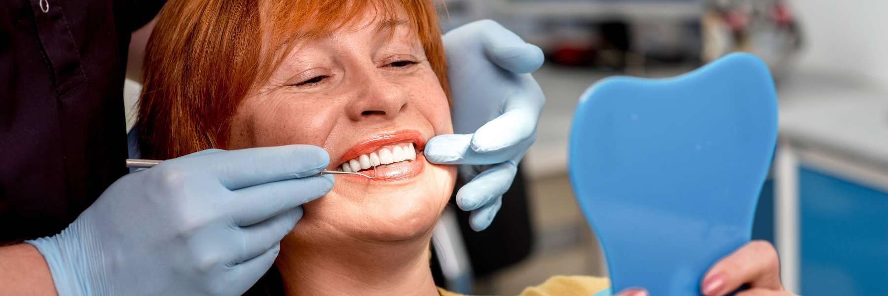 A woman at the dentist looking at her teeth