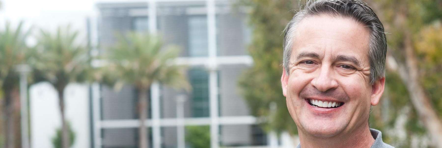 A man smiling in front of palm trees
